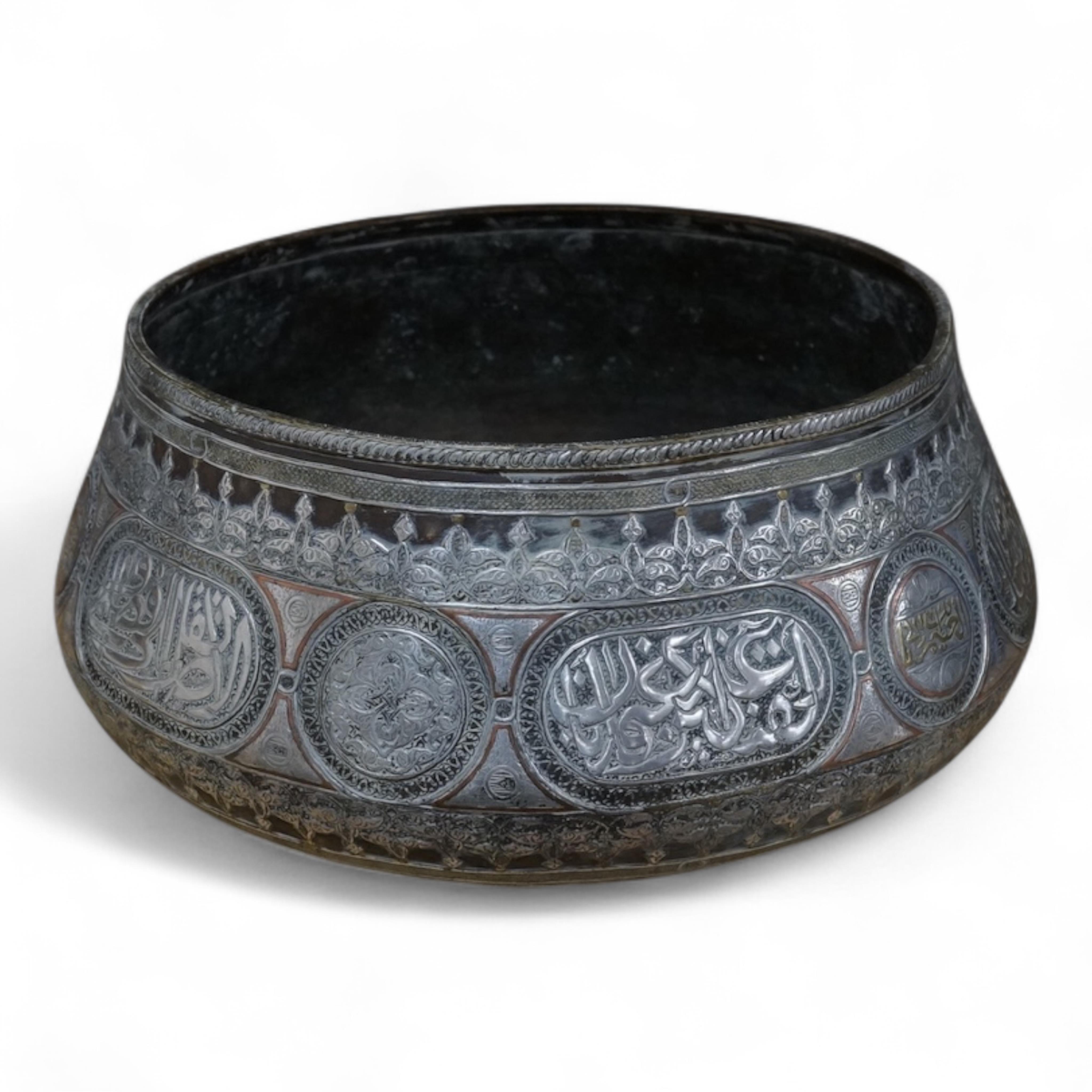 A late 19th century Mamluk style brass basin inlaid with silver and copper decoration, 29cm diameter